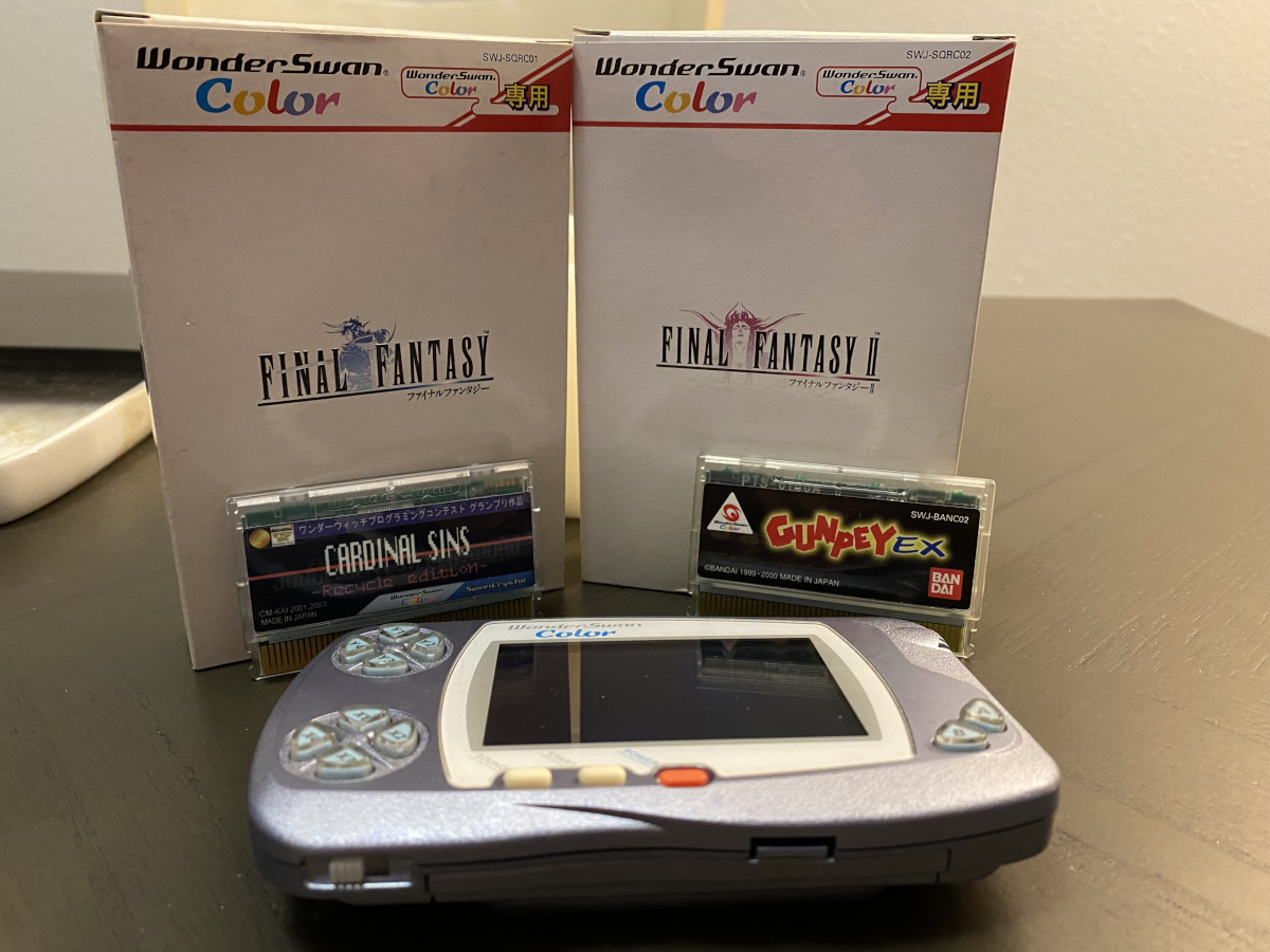 A picture showing a WonderSwan Color, loose copies of Cardinal Sins and Gunpey EX, and boxed copies of the first two Final Fantasy games